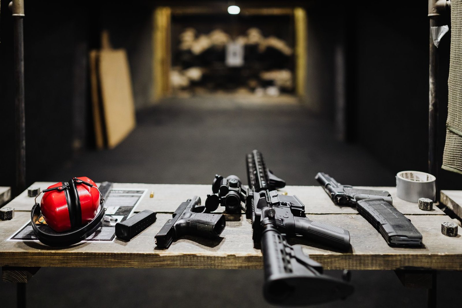 Pistols, a magazine, and a rifle on a shooting bench.